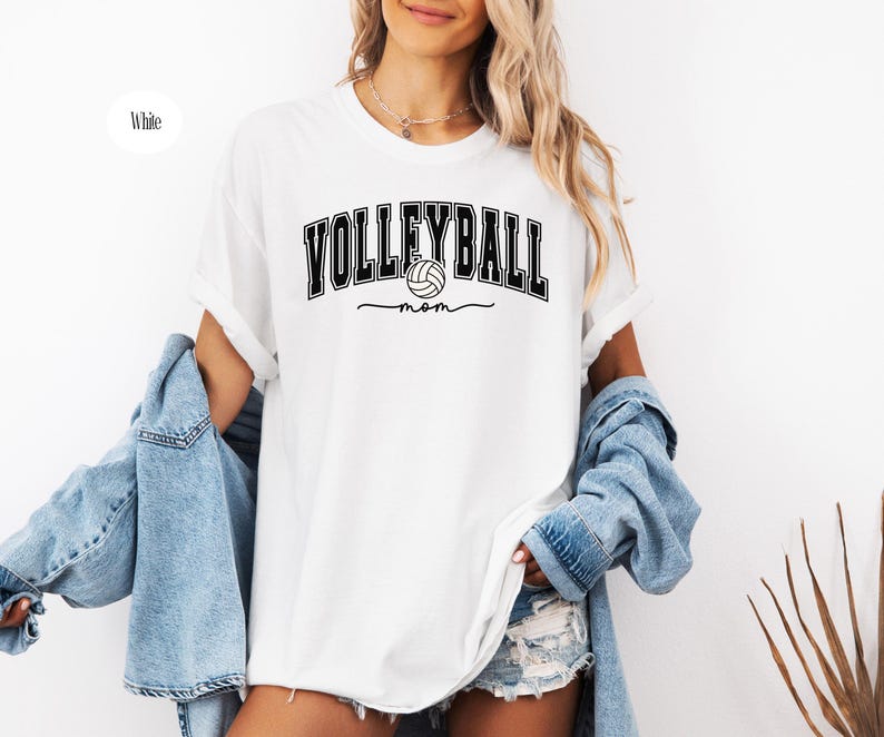 May include: White t-shirt with black text that reads "Volleyball mom" and a volleyball graphic.