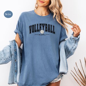 May include: A blue jean t-shirt with the text "Volleyball Mom" and a volleyball graphic.