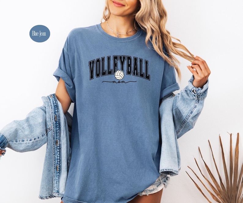 May include: A blue jean t-shirt with the text "Volleyball Mom" and a volleyball graphic.