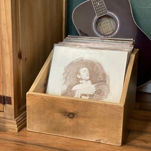 Rustic album display and storage crate sitting next to guitar and media cabinet