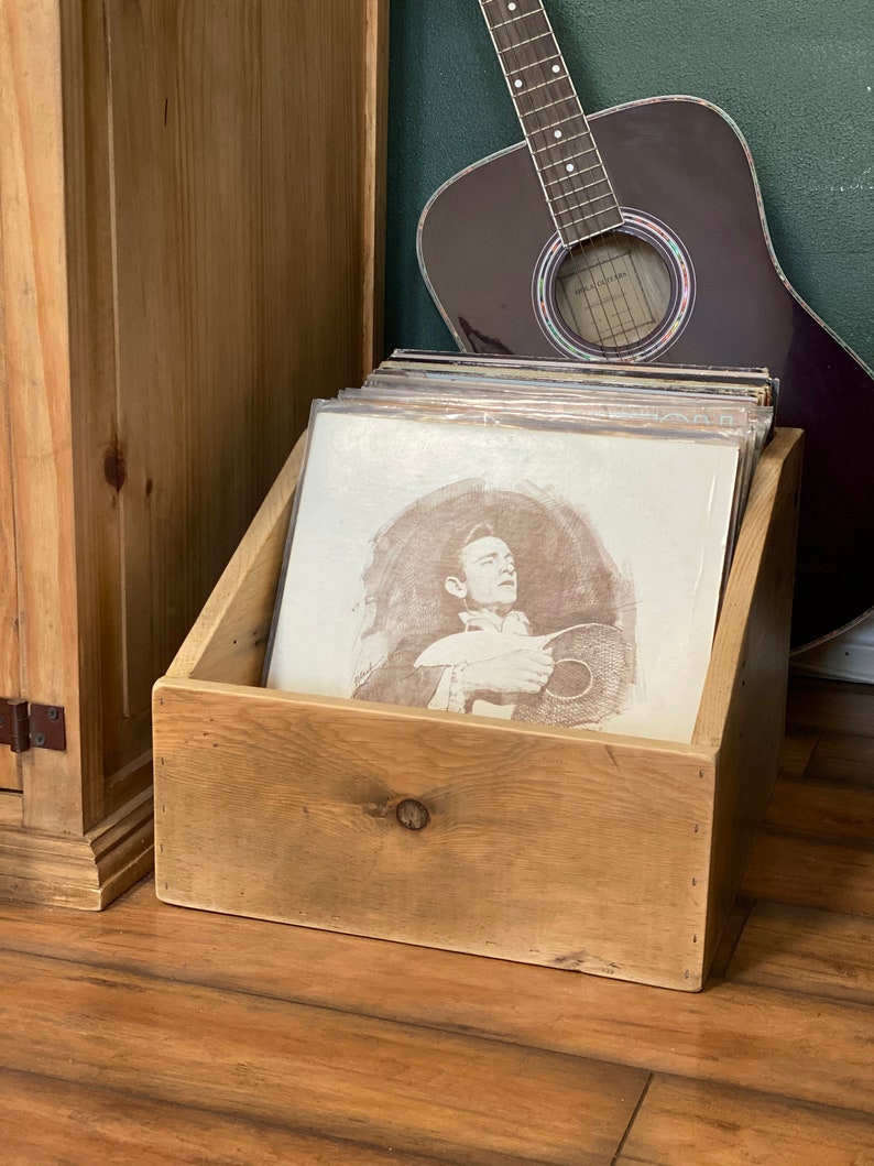 Rustic album display and storage crate sitting next to guitar and media cabinet