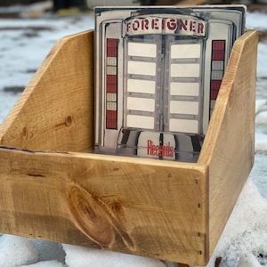 May include: A wooden record storage crate with a vintage record album inside. The album cover features a jukebox with the word "FOREIGNER" printed on it.