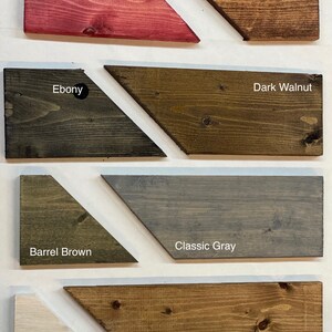 May include: Wood stain color samples in a triangular shape. The colors are Barn Red, Red Oak, Ebony, Dark Walnut, Barrel Brown, Classic Gray, Whitewash, and Special Walnut.