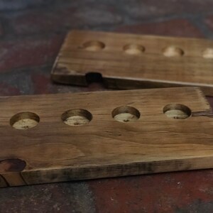 May include: Two wooden trays with circular cutouts. The top tray has four cutouts and the bottom tray has five cutouts.