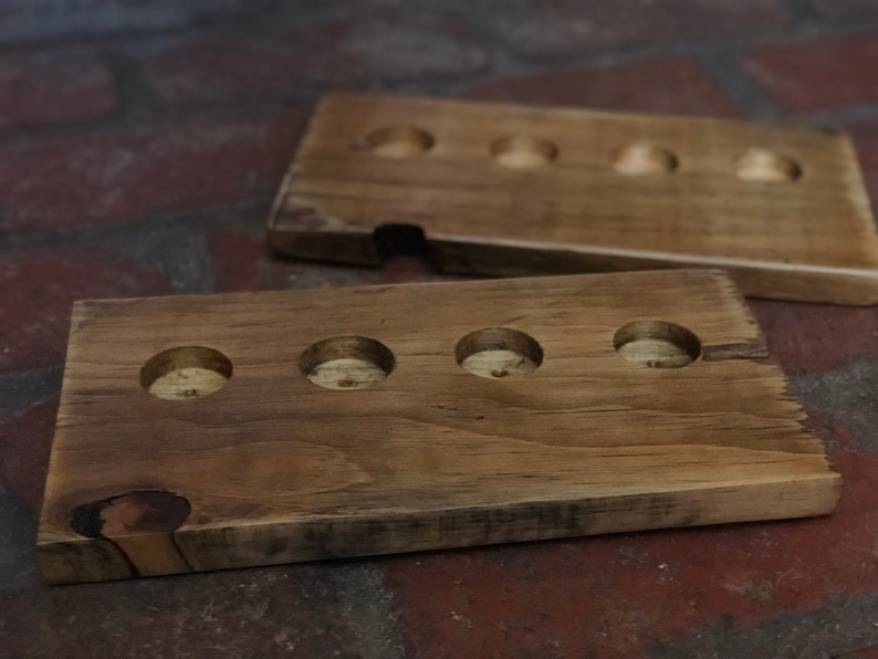 May include: Two wooden trays with circular cutouts. The top tray has four cutouts and the bottom tray has five cutouts.