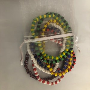 May include: A set of colorful beaded bracelets in a white organza bag. The bracelets are made with small, round beads in various colors, including red, white, blue, green, yellow, and black.