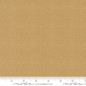 May include: A close-up of a beige fabric with a subtle woven texture. The fabric has a slightly rough, natural feel. The fabric is measured in inches with a ruler.
