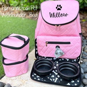 May include: Pink quilted pet carrier backpack with a paw print and the name "Willow" embroidered on the front. The backpack has two zippered compartments, a side pocket, and a black and white paw print lining. The backpack comes with two collapsible food bowls.