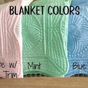 May include: Five quilted baby blankets in different colors: white, white with pink trim, mint, blue, and gray. The blankets are arranged horizontally with the text "BLANKET COLORS" above them.