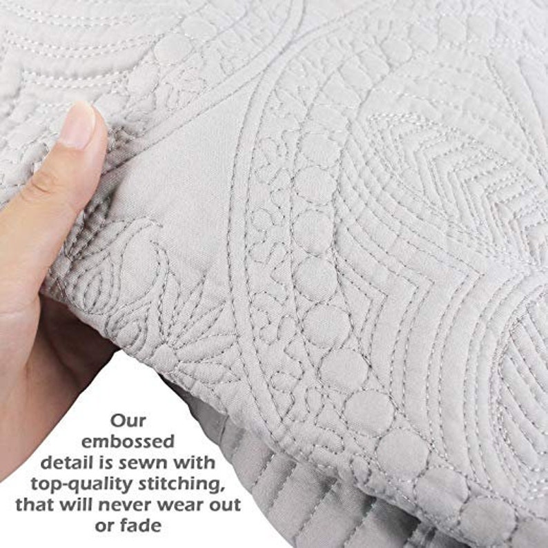 May include: Close-up of a white quilted fabric with an embossed design. The fabric has a subtle sheen and a soft texture. The text "Our embossed detail is sewn with top-quality stitching, that will never wear out or fade" is visible in the lower left corner of the image.