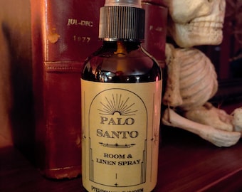 May include: A brown glass bottle with a black spray nozzle and a label that reads "Palo Santo Room & Linen Spray" and "Pteridomania Emporium".