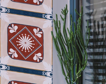 Puede incluir: Una maceta negra con una planta de cactus verde se encuentra en un alféizar de ventana. La pared detrás de la maceta tiene un patrón repetitivo de azulejos geométricos rojos, blancos y azules.