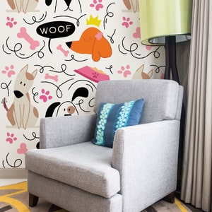 May include: A gray armchair with a blue patterned pillow sits in front of a white wall with a repeating pattern of cartoon dogs, bones, and paw prints. The text "WOOF" is included in the pattern.