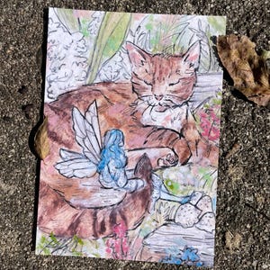Puede incluir: Una ilustraci&oacute;n de acuarela de un gato atigrado naranja durmiendo con un hada azul con alas sentada en su espalda. El gato est&aacute; rodeado de follaje verde y flores rosas.