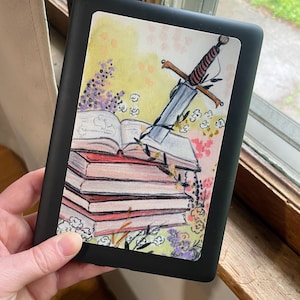 May include: A black e-reader with a colorful sticker featuring a sword sticking out of a stack of books. The sticker has a watercolor background with flowers and a yellow, orange, and pink color scheme.