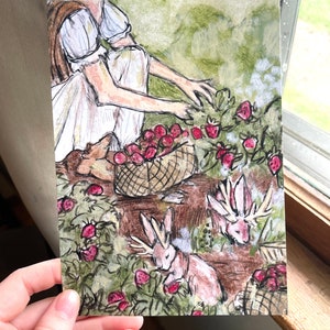 May include: Two figures in white dresses are picking strawberries in a field. A basket of red strawberries sits on a wooden table. Three rabbits with antlers are eating strawberries in the field.