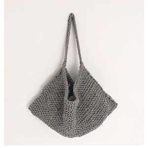 May include: A gray crocheted tote bag with a wide, flat base and two long straps.