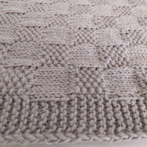 Könnte beinhalten: Nahaufnahme eines grauen gestrickten Stoffes mit einem Rautenmuster.