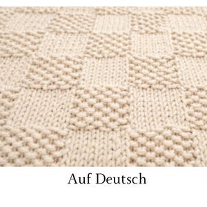 May include: A cream-colored knitted blanket featuring a repeating checkerboard pattern. The design alternates between squares of smooth stockinette stitch and squares of textured garter stitch, creating a tactile grid across the entire surface.