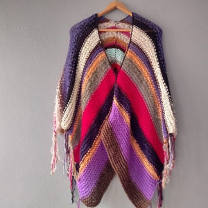 May include: A multi-colored crocheted poncho with fringe. The poncho is made with a variety of colors, including purple, red, brown, and beige.