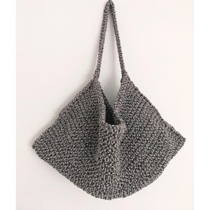 May include: A gray crocheted tote bag with a wide, flat base and two long straps.