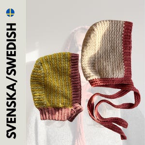 Puede incluir: Dos gorros tejidos a mano. Uno es crema y rojo, con lazos. El otro es amarillo y verde con un borde rojo. Los gorros son probablemente para bebés o niños pequeños.