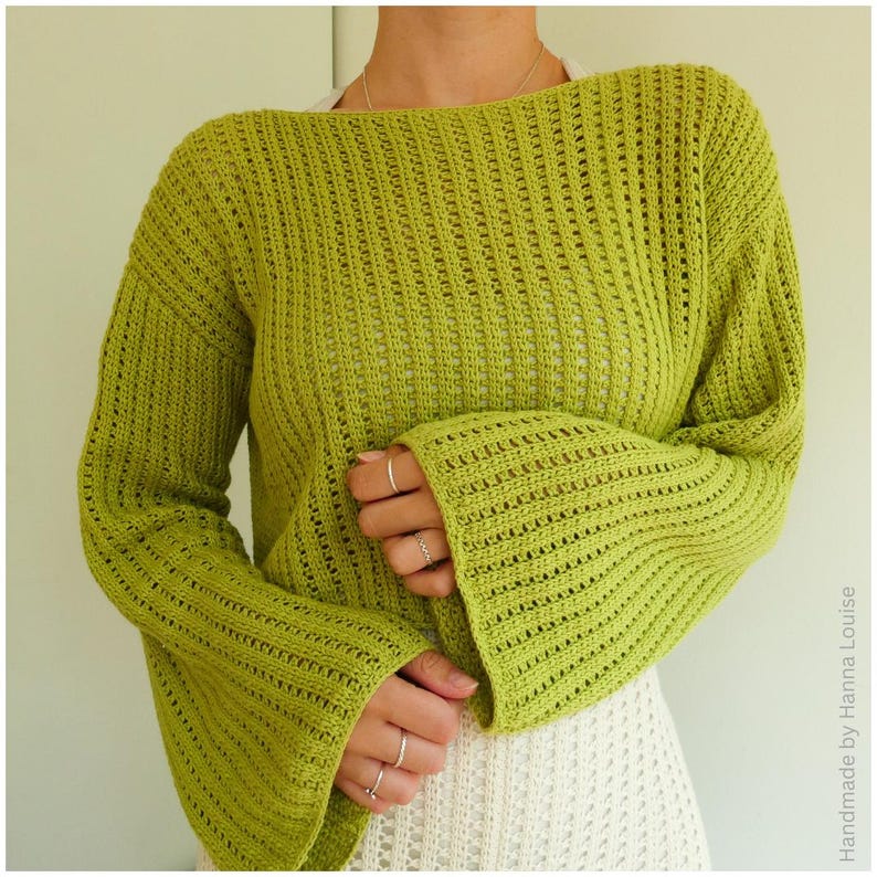 May include: A green crocheted sweater with bell sleeves. The sweater has a loose fit and a wide neckline.