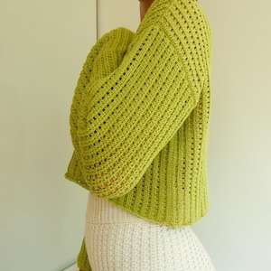 May include: A lime green crocheted sweater with a loose fit and a slightly cropped length.