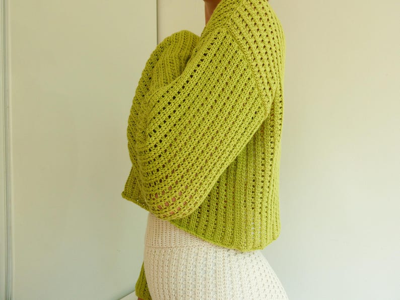 May include: A lime green crocheted sweater with a loose fit and a slightly cropped length.