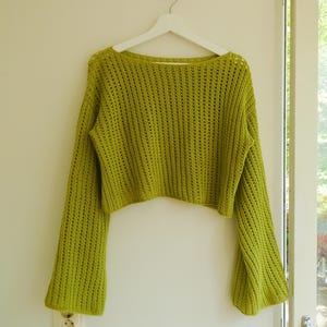 May include: A lime green crocheted sweater with long bell sleeves and a cropped fit.