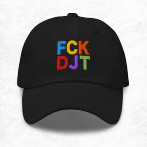May include: Black baseball cap featuring the embroidered text "FCK DJT" in rainbow colours. The hat has a curved peak and a fabric strap closure. A classic, casual style.