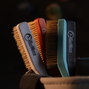 May include: Four different colored brushes with brown bristles and the text "BADWATER" printed on the handles. The brushes are in a brown and white pouch.