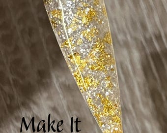May include: Clear nail swatch with gold and silver glitter and gold leaf flakes. The text "Make It Rein" is written in black script at the bottom of the image. The nail swatch is held by a clear plastic stick.