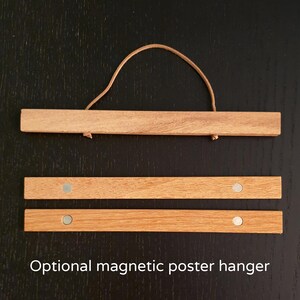 Peut inclure: Un ensemble de trois supports magn&eacute;tiques pour affiches en bois. Les supports sont en bois naturel et ont une finition brune. Chaque support a deux aimants argent&eacute;s en bas. Le support sup&eacute;rieur a une boucle en cuir marron.