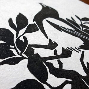 Peut inclure: Gravure sur linol&eacute;um en noir et blanc d'un oiseau perch&eacute; sur une branche. L'oiseau est de profil, la t&ecirc;te tourn&eacute;e de c&ocirc;t&eacute;. La branche est compos&eacute;e de plusieurs feuilles.