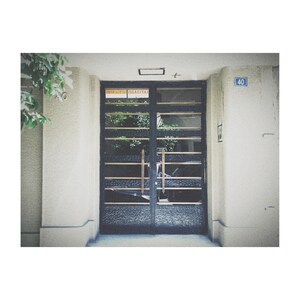 May include: A black metal door with a glass panel and horizontal bars. The door has two gold handles and a sign that reads "Emergency Exit". The door is in front of a white wall with the number "40" on it.
