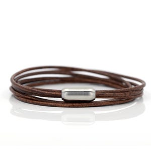May include: A brown leather bracelet with a silver metal clasp. The bracelet is made of multiple strands of leather.