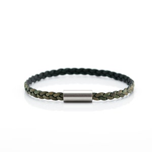Peut inclure: Un bracelet en cuir tressé avec un fermoir en métal argenté. Le bracelet est vert et noir.