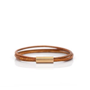 May include: A brown leather bracelet with a gold metal clasp.