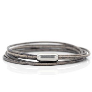 May include: A multi-strand leather bracelet with a silver metal clasp. The bracelet is made of several thin strands of leather that are woven together.
