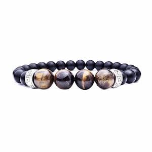 Op de afbeelding: Een zwarte en bruine kralen armband met zilveren accenten. De armband heeft vier grotere tijgeroog kralen en kleinere zwarte kralen.
