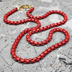 May include: A red chain necklace with a gold clasp. The chain is made of small, round links.