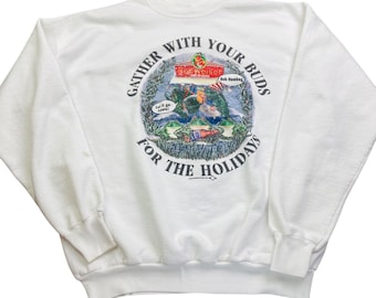 May include: White sweatshirt with a crew neck and long sleeves. The front features a circular graphic with the Budweiser logo and the text "Gather with your buds for the holidays". The graphic includes images of fish, a lake, and a flag.
