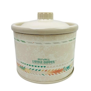 Peut inclure: Un appareil de cuisson électrique en grès Rival Little Dipper de couleur crème avec son couvercle assorti. Le corps cylindrique présente une texture marbrée et une bande décorative aux motifs géométriques verts, orange et beige.