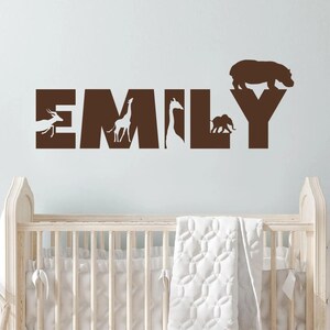 Peut inclure: Autocollant mural en vinyle marron avec le nom "EMILY" &eacute;crit en grandes lettres. Chaque lettre contient la silhouette d'un animal diff&eacute;rent&nbsp;: une gazelle, une girafe, une girafe, un &eacute;l&eacute;phant et un hippopotame.