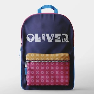 Peut inclure: Un sac &agrave; dos bleu avec une bordure rose et une poche &agrave; motifs jaunes et roses. Le sac &agrave; dos porte le nom "OLIVER" &eacute;crit en lettres blanches sur le devant avec des silhouettes d'animaux.