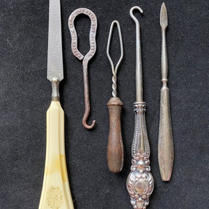 May include: Five vintage tools with different handles and metal tips. The tools include a nail file, a hook, a needle threader, a hook, and a cuticle pusher.