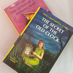 May include: Two vintage Nancy Drew mystery books. One book is titled "The Quest of the Missing Map" with a pink cover. The other book is titled "The Secret of the Old Clock" with a blue cover and a woman in a green dress.