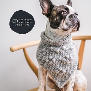 May include: A gray crocheted dog bandana with a textured, bumpy design. The bandana is worn by a French bulldog sitting on a wooden chair. The text "crochet pattern" is visible in the upper left corner of the image.