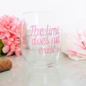 May include: A clear glass wine glass with the pink text "The limit does not exist" printed on the side.